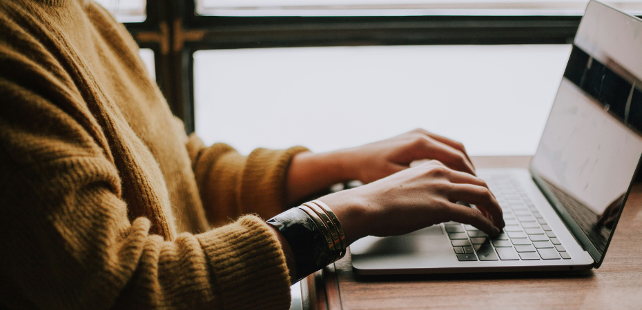 Close up photograph of the arms of a person using a laptop.