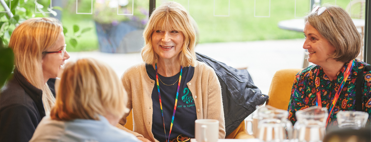 A photo of a group of women at an event, sat on sofas and in conversation