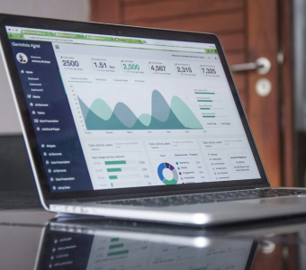 Photograph on an open laptop displaying graphs and data