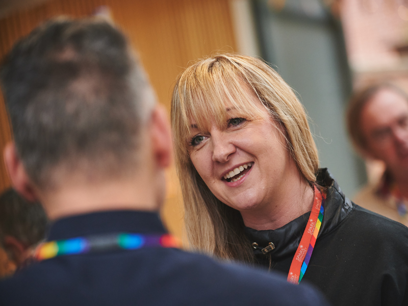 A photo of a member of the Spark Somerset team in happy conversation with a man whose back is turned towards the camera.