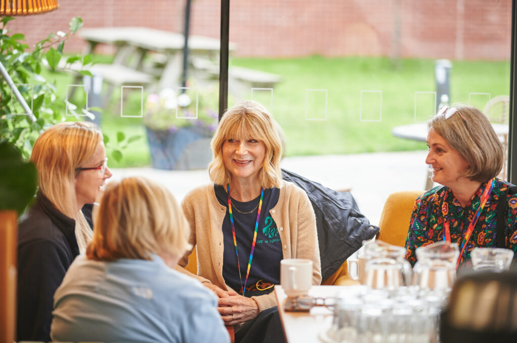 Four attendees having a conversation at a table, smiling.