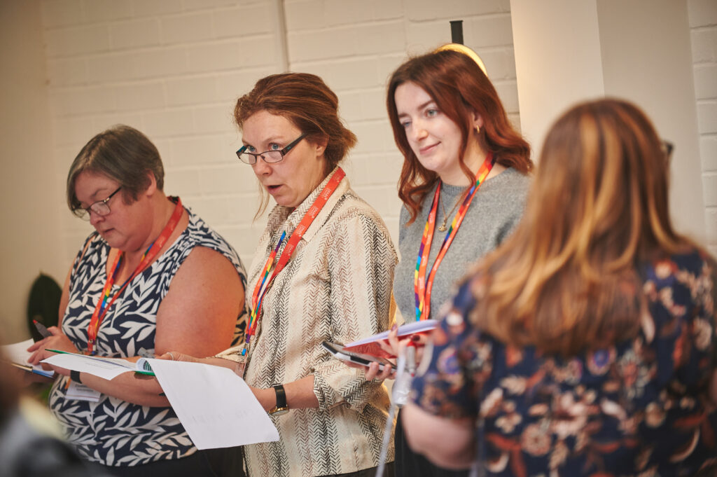 Three attendees standing in a row, holding notepads.