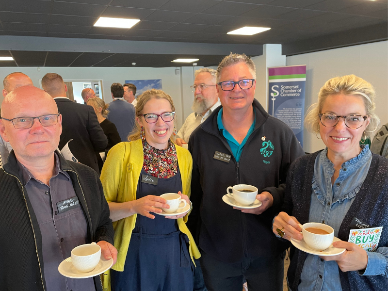 A photo from attendees of a Spark Somerset partnership event with Somerset Chamber of Commerce. The are holding cups of tea and coffee and smiling at the camera.