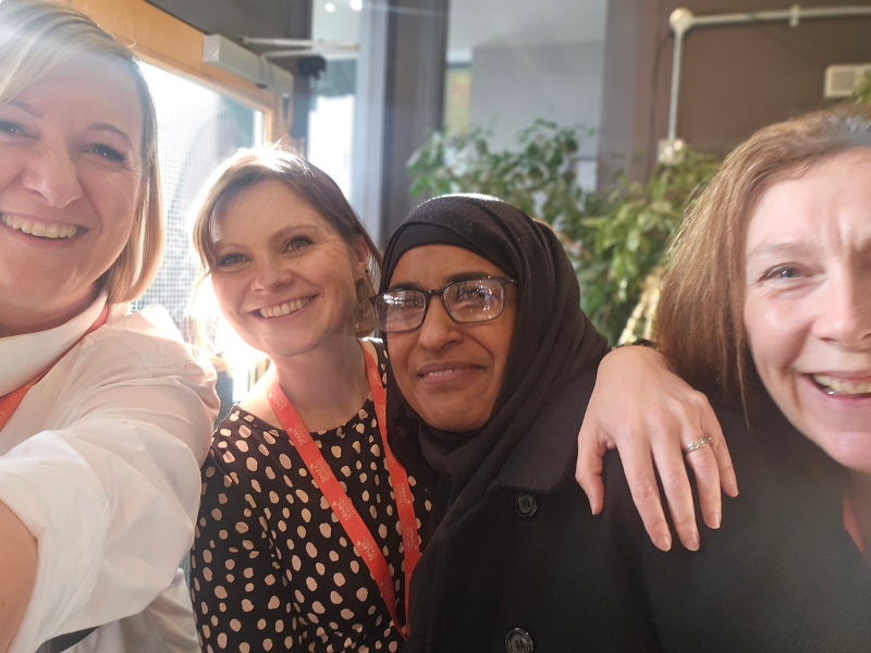 Selfie style photograph of a group of people smiling at the camera.