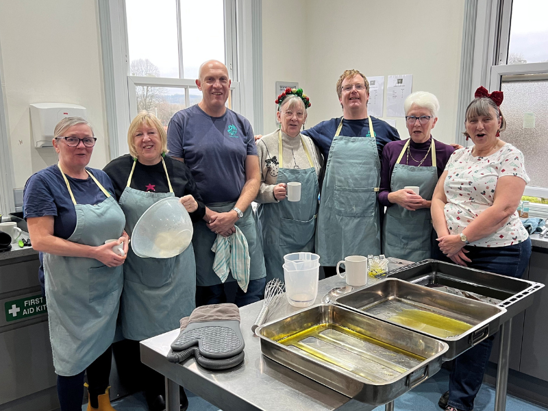 Photograph of a group of volunteers standing in a kitchen smiling at the camera.
