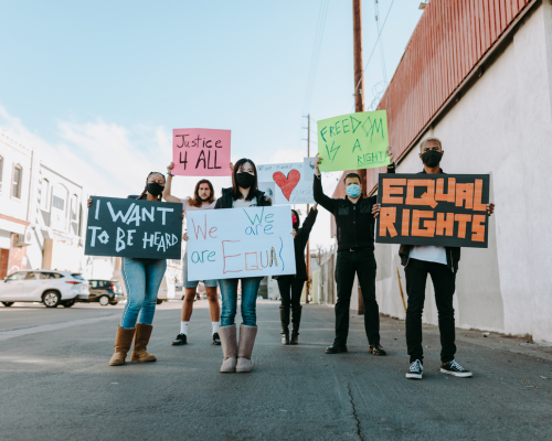 A diverse group of people holding placards and posters relating to equality and hate crimes.