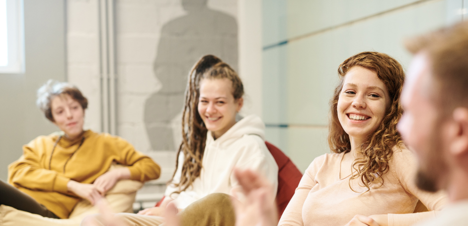 Photograph of a group of smiling people seated and having a conversation.