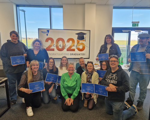 A photo of a previous cohort of learners posing with their certificates of completion.