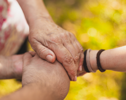 An image depicting a close-up of three people holding hands as if supporting each other.