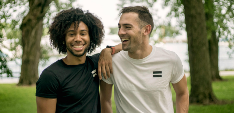photograph of two young men smiling at the camera in an outdoor setting
