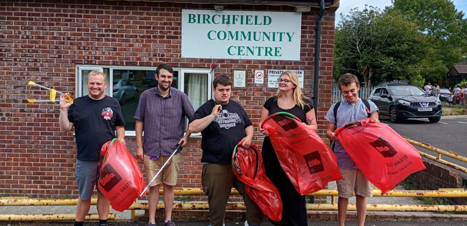 A photo of volunteer litter-pickers posing with red litter bags outside of Birchfield Community Centre