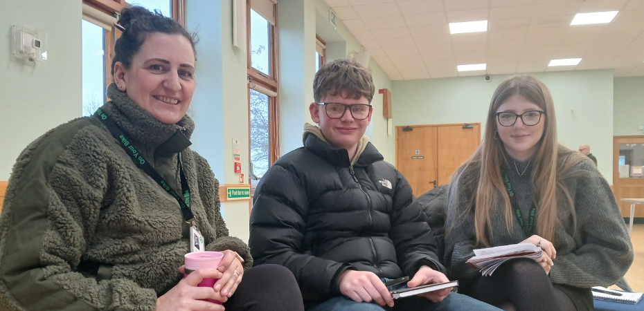 Photograph of Tracey Mock and two other course attendees, they are sitting alongside each other in a village hall and smiling at the camera.