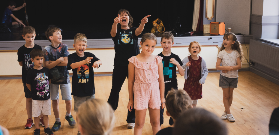 A picture from the Somerset Youth Theatre showing a group of young people smiling, laughing, and pointing