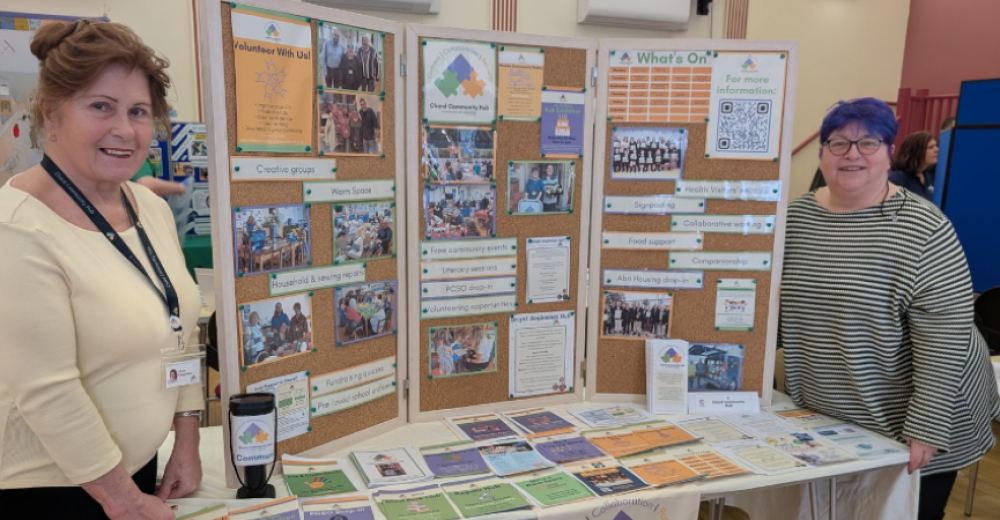 Photo of two smiling women standing next to a display board at an event