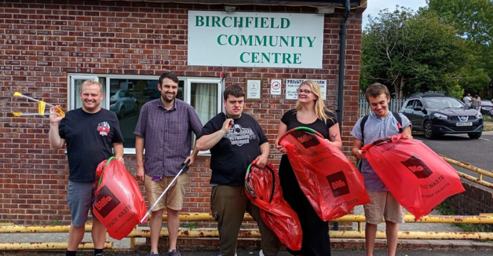 A photo of volunteer litter-pickers posing with red litter bags outside of Birchfield Community Centre