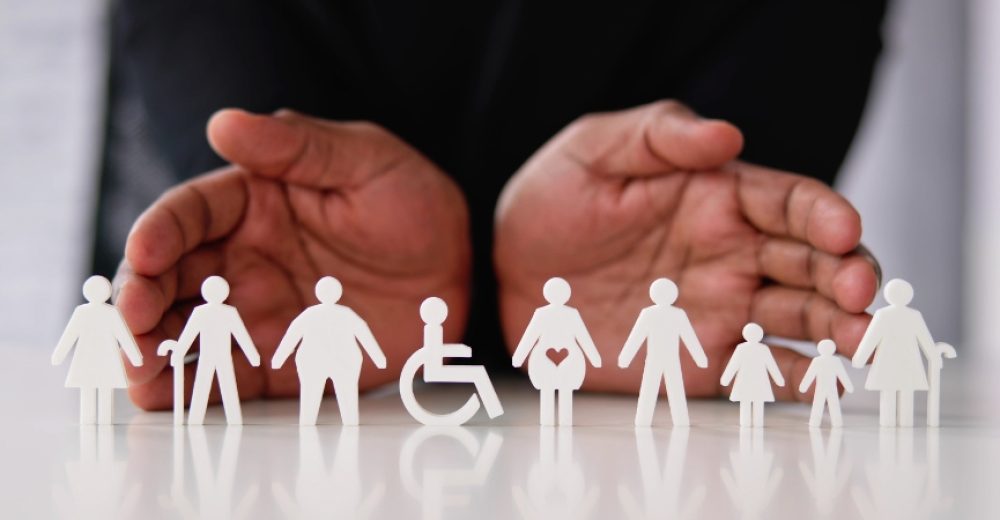 Photograph of a pair of open hands behind several figures depicting protected characteristics.