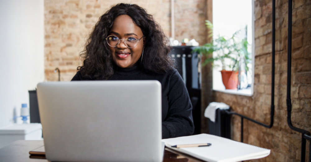 Black woman wearing glasses and working on a laptop
