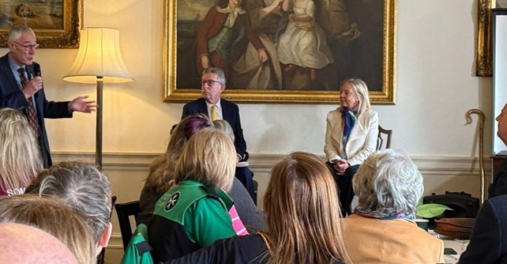 Photograph of attendees at an event, backs to the camera, looking at the speakers