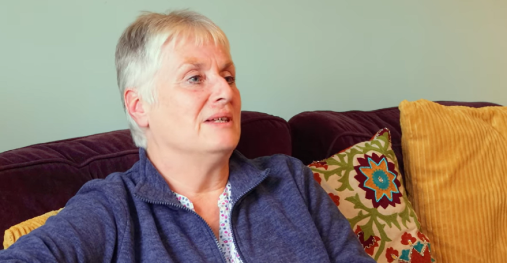 Image of Sue Crisfield, sat on a sofa, in conversation with someone off camera