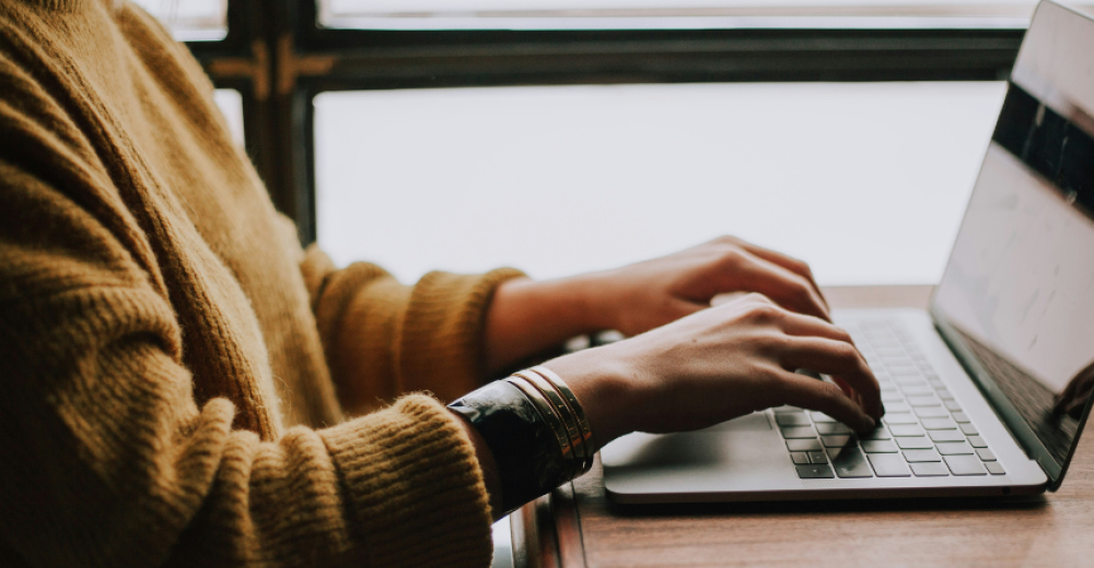 Close up photograph of the arms of a person using a laptop.