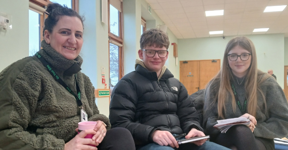 Photograph of Tracey Mock and two other course attendees, they are sitting alongside each other in a village hall and smiling at the camera.