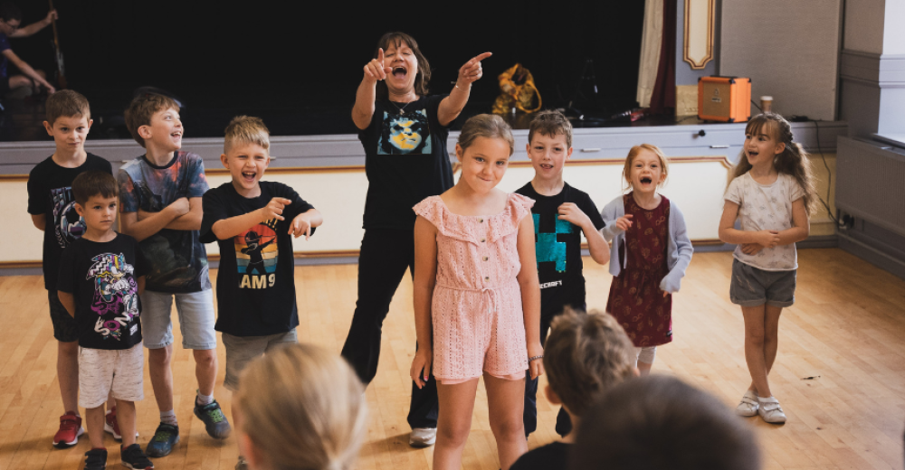 A picture from the Somerset Youth Theatre showing a group of young people smiling, laughing, and pointing